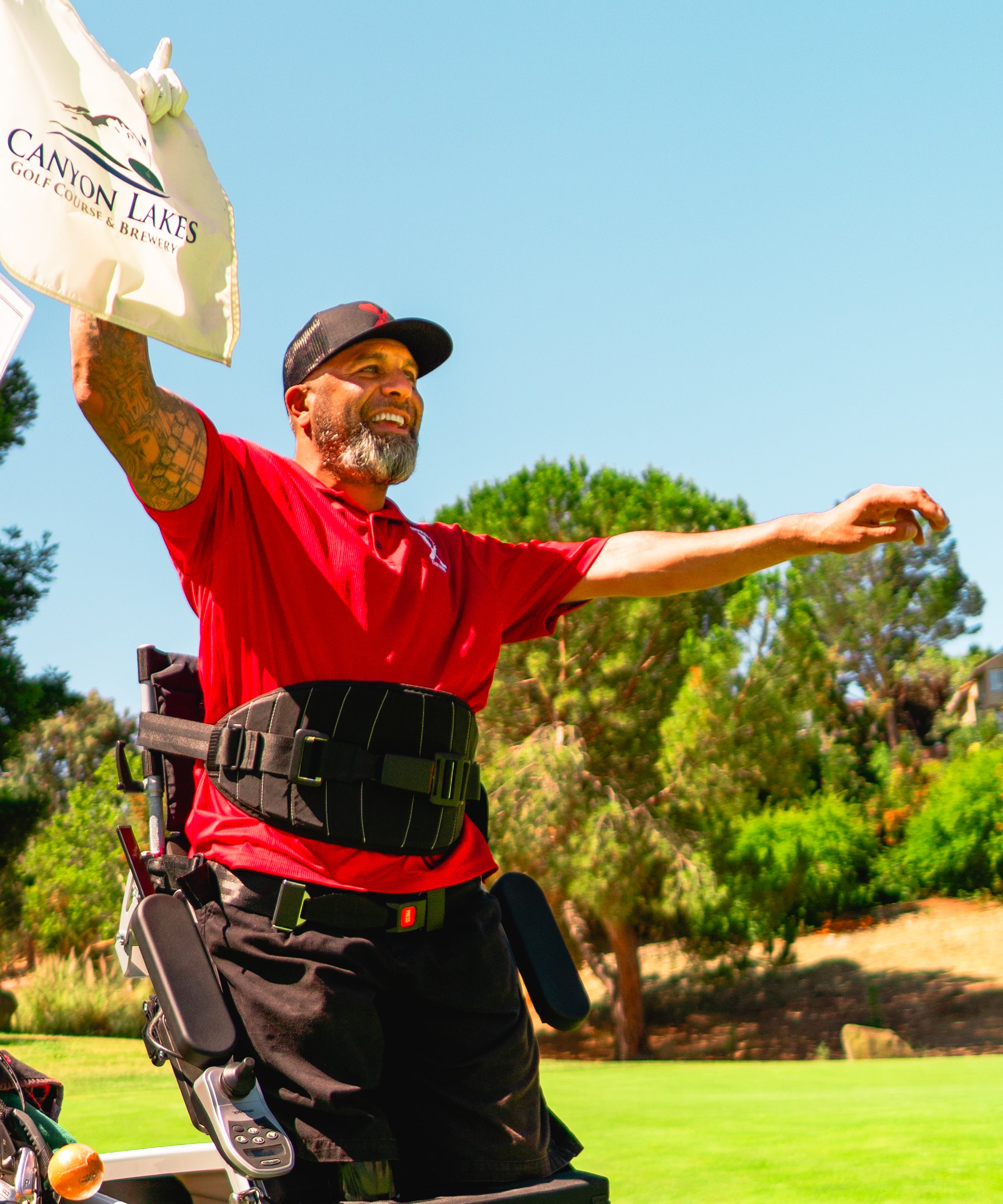 Candid photo of Amplife® Foundation & Amplife® Founder Abdul Nevarez celebrating and holding the flag on his 1st one-armed hole-in-one as a right above knee amputee with severe nerve damage in his left arm and left leg in an adaptive golf cart at Canyon Lakes 5th
