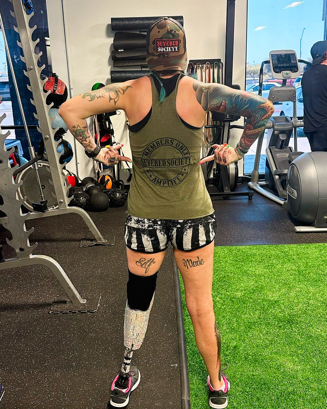 Photo behind Team Amplife® Ambassador SuZanne Jacobsen in the gym pointing at her Severed Society® Tank Top
